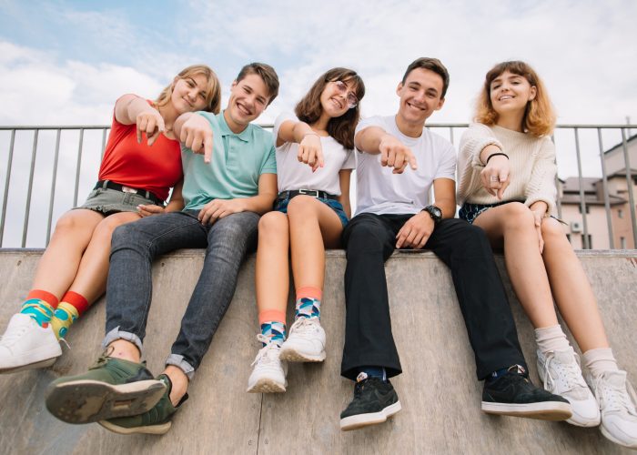 Summer holidays and teenage concept - group of smiling teenagers hanging out outside.